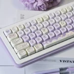Playful Taro Paste Kitten PBT dye-sub MOA keycaps set in soft pastel purple and white, showcasing cute kitten and taro designs from different perspectives.