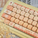 Close-up of a whimsical baking cat artisan keycap set in soft pastel colors, highlighting its charming detail and PBT MOA profile from a new angle.