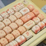 Charming baking cat artisan keycap set, playfully angled, highlights its whimsical pastel design and soft bread motifs. An adorable PBT MOA accent.