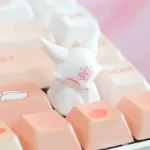 Unique handcrafted artisan resin keycap, showing a mythical fox among delicate peach blossoms. Translucent resin reveals intricate details, evoking artistic design.