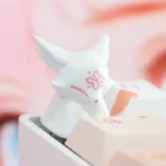 Handcrafted artisan resin keycap featuring a mythical fox and delicate peach blossoms, showcasing unique translucent detail from a different angle.