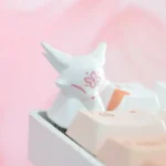 Stunning handcrafted artisan keycap showcasing a mythical fox amidst delicate peach blossoms, encased in luminous translucent resin.