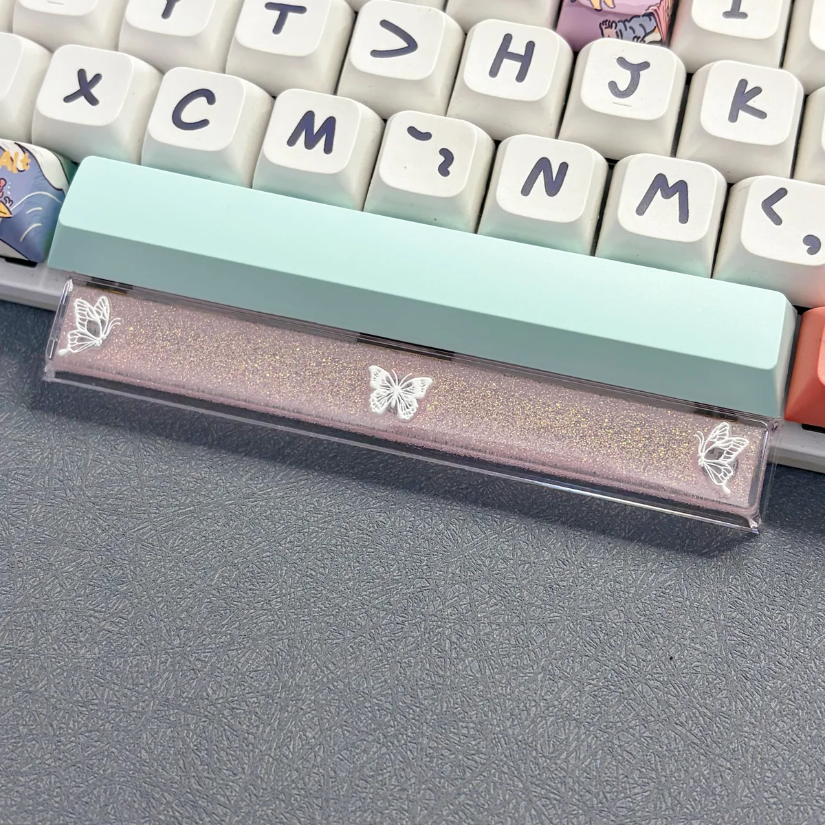 Close-up of a handcrafted translucent butterfly artisan space key keycap, showcasing its ethereal glow and delicate resin details on a mechanical keyboard.