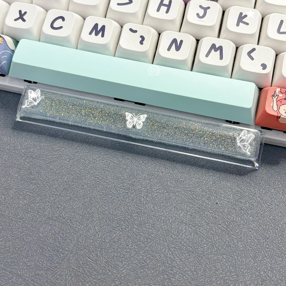 Close-up views of a handcrafted translucent butterfly artisan space key keycap, showcasing its ethereal resin details and delicate glowing aesthetic.