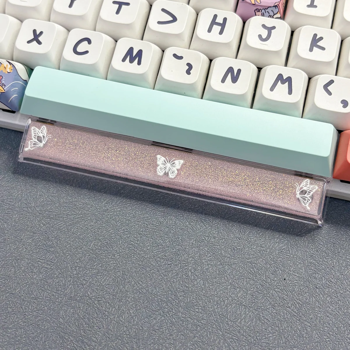 A close-up view of a handcrafted translucent butterfly artisan space key keycap, showcasing its delicate resin details and ethereal glow from various angle.