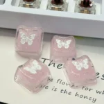 Ethereal pink butterfly resin keycap gallery, showing its handcrafted translucent design with shimmering glitter. Multiple angles reveal this dreamy design.