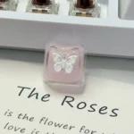 Handcrafted ethereal pink butterfly resin keycap, new angle. Highlights translucent wings, shimmering pink glitter, and dreamy artistic details.