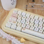 A playful close-up of the Sweet Treat MOA PBT Cake Keycap Set, showcasing its adorable cream design and unique MOA profile from various angles.