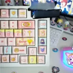 Close-up of Cardcaptor Sakura & friends keycaps set, showcasing vibrant pink and gold magical girl anime motifs from an appealing angle. An iconic keyboard set.