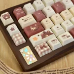 Adorable PBT dye-sublimated Coffee Bear keycap set, shown from a playful angle. Its charming cartoon design features warm earthy tones, a whimsical keyboard.