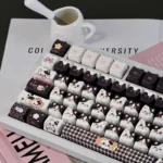 Playful side view of the unique artisan Whimsical Cow Cat keycap set, highlighting its adorable black and white cow-patterned head for mechanical keyboard.