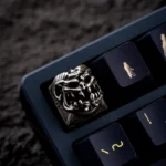 An artistic, angled shot of the handcrafted Disaster Relief Demon Keycaps, revealing its intricate metallic demon details and dark industrial.