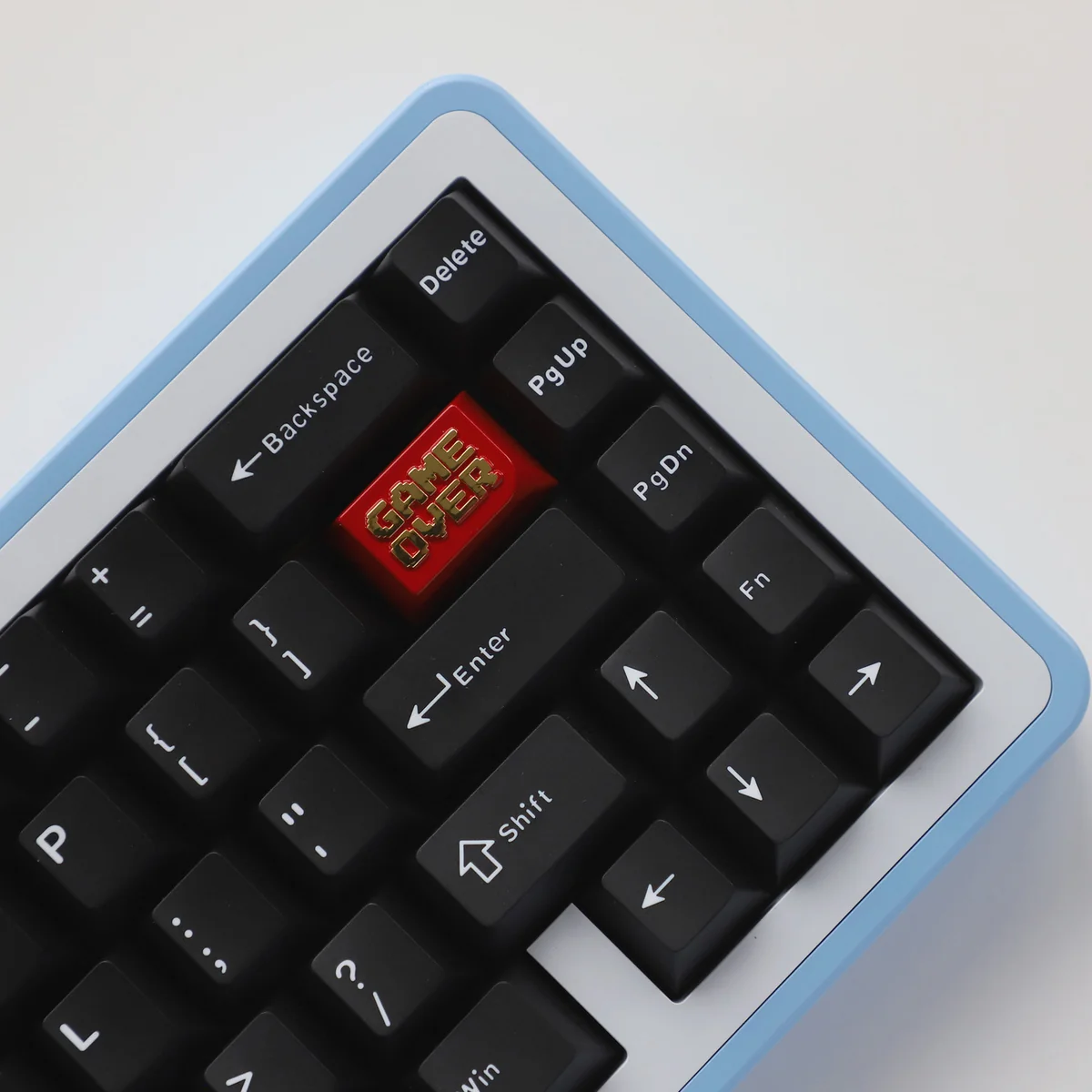 A premium zinc alloy Game Over Keycap featuring a bold red and gold metallic design and clear 'Game Over' lettering, showcasing its industrial finish.