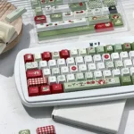 Apple PBT keycaps set, vibrant green and red dye-sub design, durable Cherry profile, shown from an engaging angle, highlighting fresh, playful charm.