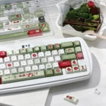 Vibrant green and red Apple PBT Keycap Set, shown from various angles, highlighting the durable dye-sublimated fresh apple deisgn.