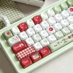 Green & Red Apple PBT Keycaps Set feature vibrant green-red apple designs, durable dye-sub PBT, shown from a playful angle.