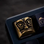 Pure copper Sanxingdui Mask Keycap, a unique mystical charm. Detailed views show its ancient bronze mystique and whimsical design.