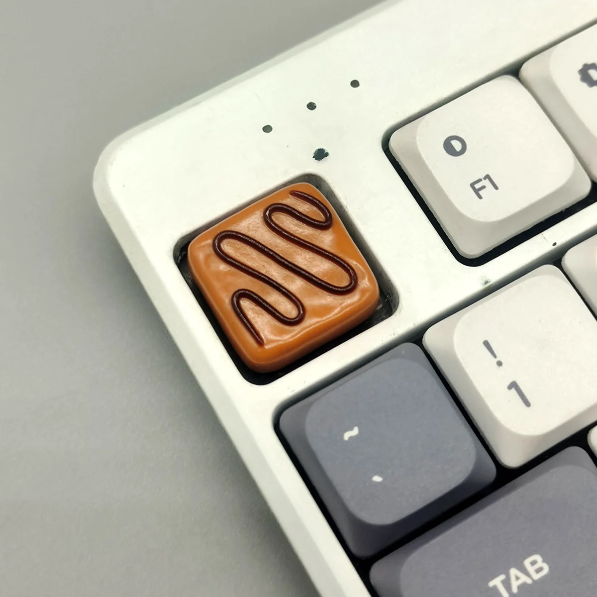 Close-up of a handcrafted gourmet chocolate artisan resin keycap, showcasing warm striped caramel hues, evoking a delicious aesthetic.