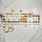 Adorable Maltese dog PBT keycaps set showcased from various angles, featuring charming line art and a playful spa theme in warm tones.
