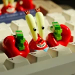 Angled view of the iconic Mr. Krabs resin artisan keycap, showcasing its intricate SpongeBob character details, vibrant colors, and money-themed base.