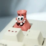 A vibrant, handcrafted Patrick Star artisan keycap for mechanical keyboards, showcasing its iconic, goofy design from multiple playful angles.