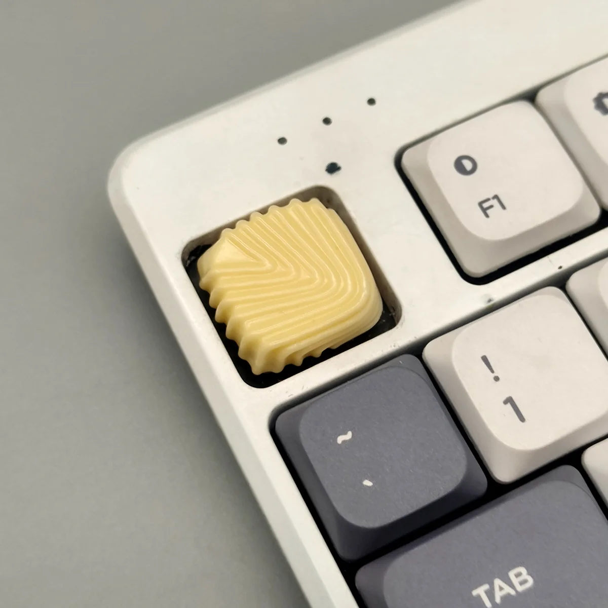 Chocolate low-shaft resin keycap in creamy yellow with an organic shell texture, evoking a delectable dessert. Handcrafted for premium keyboards.