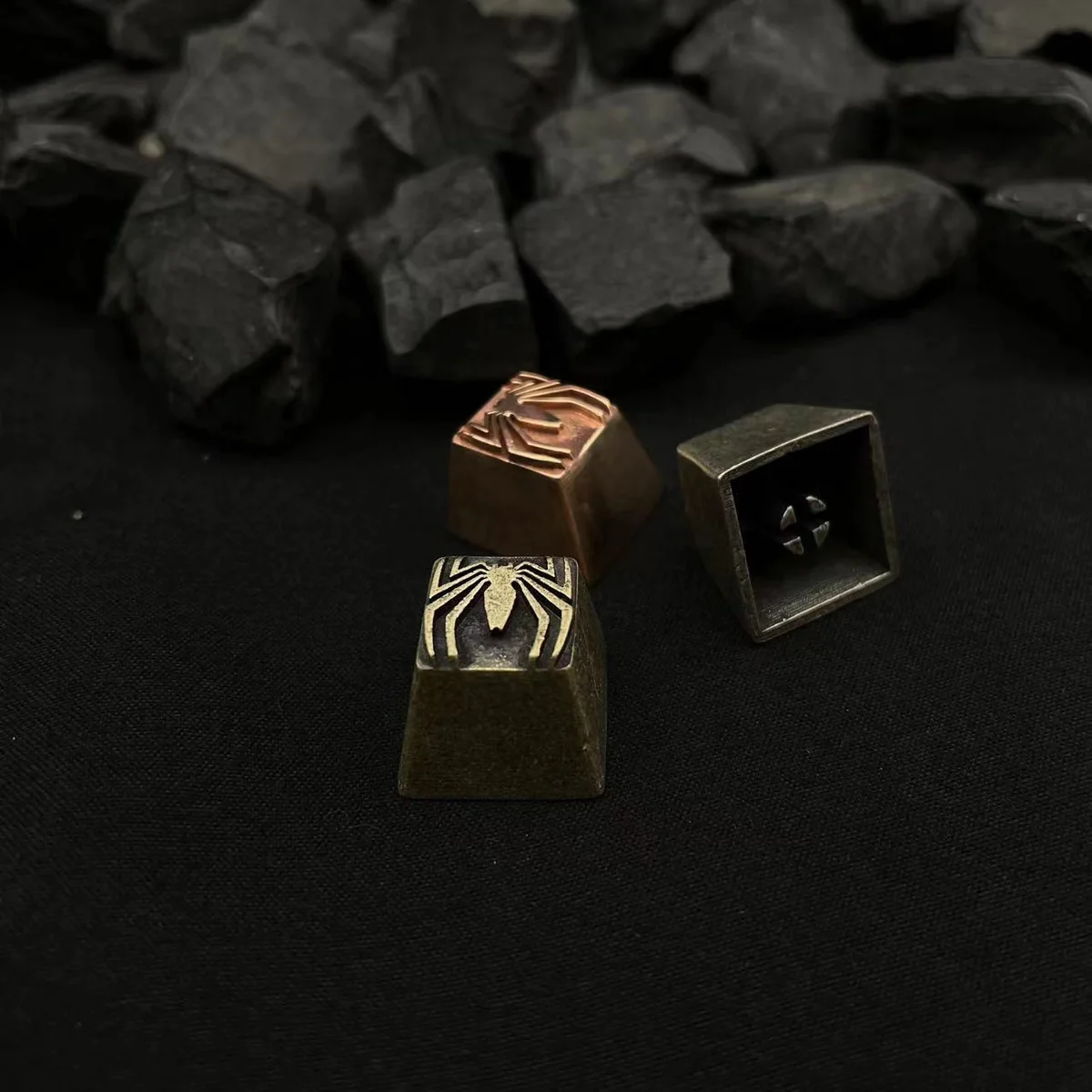 Close-up of a pure copper Spider-Man logo artisan keycap, showcasing its intricate retro design and vintage patina from multiple angles.