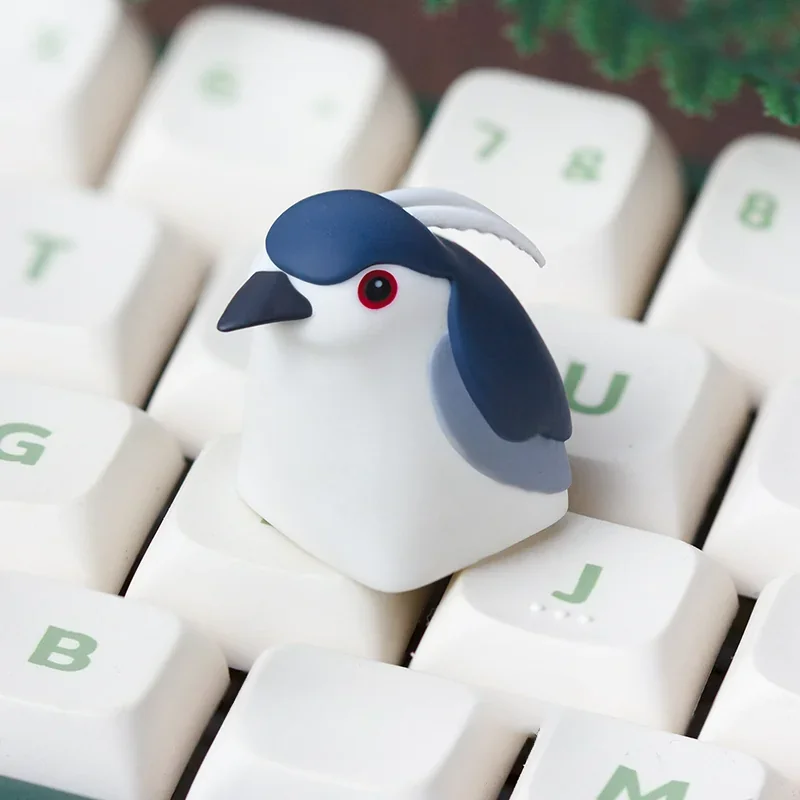 Intricate handcrafted Night Heron artisan keycap, made of resin, displaying its ethereal nature aesthetic from a unique angle for custom keyboards.
