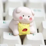 A playful artisan resin keycap featuring a whimsical pig character enjoying a snack, showcasing the vibrant handcrafted detail and unique design.
