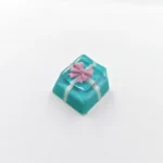 Close-up of a handcrafted resin gift box keycap, showcasing the delicate bowknot and translucent resin texture from an artistic angle.