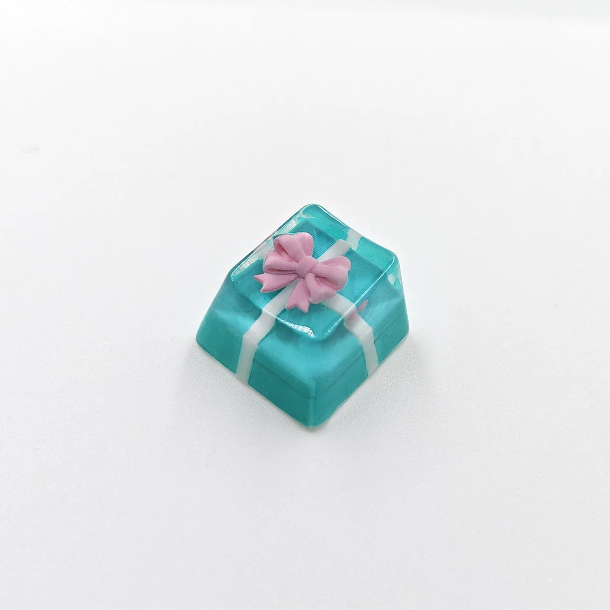 Close-up of a handcrafted resin gift box keycap, showcasing the delicate bowknot and translucent resin texture from an artistic angle.