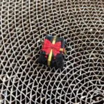 Artistic handcrafted resin ESC keycap, showcasing a miniature black gift box adorned with a delicate gold bowknot ribbon, a unique custom keyboard accent.