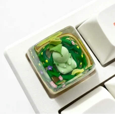 Vibrant handcrafted Chikorita Pokemon SA keycap, sculpted from translucent resin with a playful glow, shown on a mechanical keyboard.