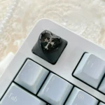 Close-up view of the premium Chrome Hearts Keycap, showcasing its iconic gothic cross and heart design with mysterious foggy transparency from multiple angles.