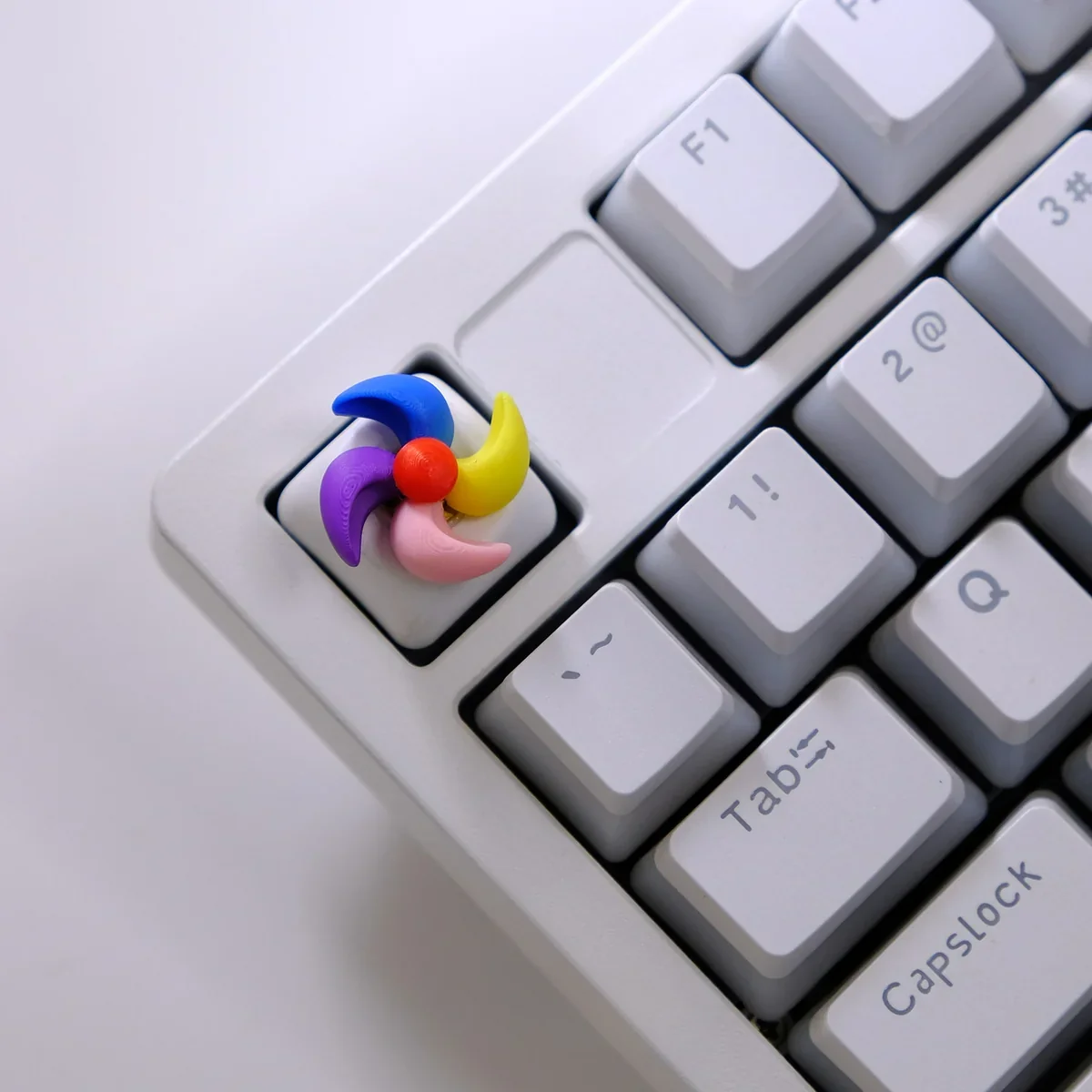 Handcrafted rotating colorful spinning windmill keycap from a unique angle, highlighting its vibrant hues, intricate miniature design, and whimsical design.