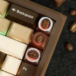 Close-up of an Artisan Coffee Bean Keycap, showcasing real coffee beans artfully encased in clear, warm-toned handcrafted resin from multiple angles.