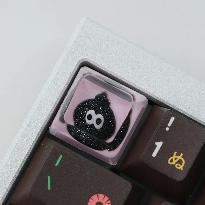Close-up of a handcrafted resin artisan keycap, showcasing its unique glitter ink drop design with sparkling pigments suspended in enchanting fluid design.
