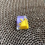 Close-up of a vibrant handcrafted graffiti resin ESC keycap, showcasing its unique abstract splatter art and bold, contrasting colors from an upward angle.