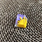 Close-up of a vibrant handcrafted graffiti resin keycap, showcasing its unique splatter art design, bold contrasting colors, and intricate details.