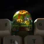 A unique handcrafted epoxy resin succulent keycap, showcasing a vibrant miniature succulent plant encapsulated in crystal-clear resin, viewed from angle.