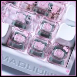 A collection of playful Hello Kitty translucent PC Supplement Keycap Set, shown from different perspectives to emphasize their clear pink glow and iconic whimsical design.