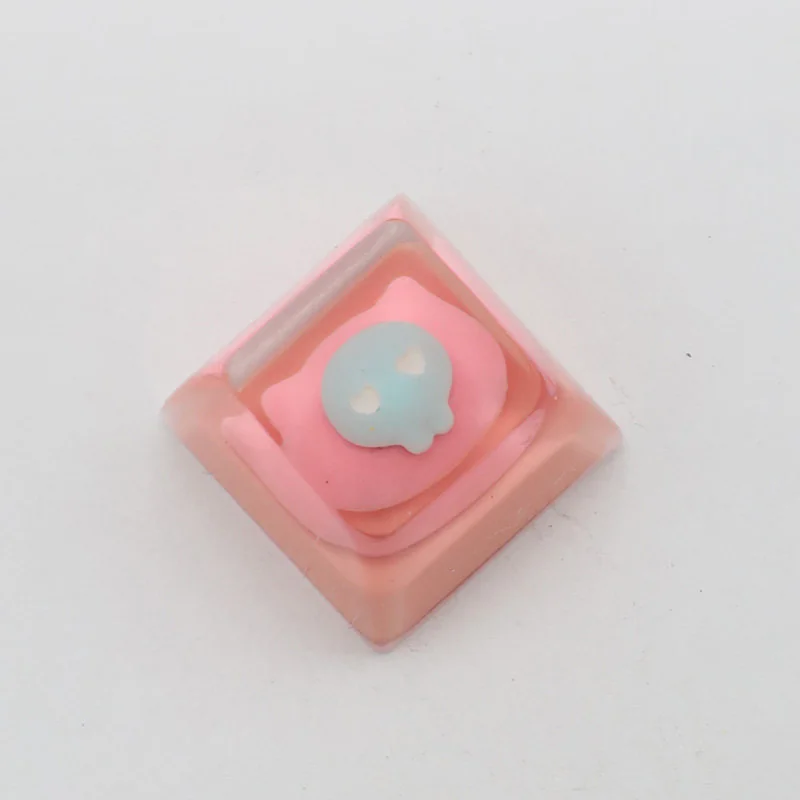 Whimsical pink cat keycap, handcrafted from luminous resin, shown from a playful, distinct angle, highlighting its adorable details. A charming keyboard.