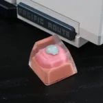 Close-up views of a handcrafted whimsical pink cat keycap, showcasing its adorable resin details and charming design from various angles.