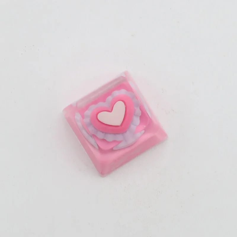 Handcrafted pink heart keycap, showcasing its charming embedded heart in smooth, glossy resin from various angles, a sweet keyboard accent.