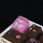 Handcrafted pink heart keycap, showcasing its charming resin design and smooth, glossy finish from a detailed, playful perspective, a sweet keyboard.
