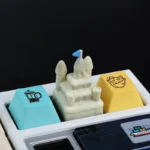 Artisanal 3D sandcastle resin keycap, showcasing its intricate miniature turrets and walls from a detailed side view, evoking serene beach day dreams.
