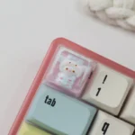 Adorable handcrafted Sanrio pajama ESC keycap close-up, showcasing beloved characters in cozy sleepwear and a vibrant resin finish, a charming desk.