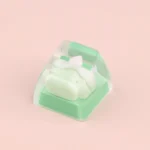 A whimsical, handcrafted dessert keycap featuring a miniature strawberry and green grape cake, adding a sweet, charming touch to any keyboard.