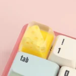 A charming, handcrafted cheese keycap shaped like a miniature dessert triangle, adding a whimsical and unique accent to any desk setup.