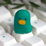 Close-up of a whimsical artisan resin duck keycap, showcasing its charming, smooth, vibrant finish from multiple adorable angles.